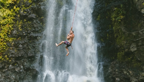 Main on rope by waterfall